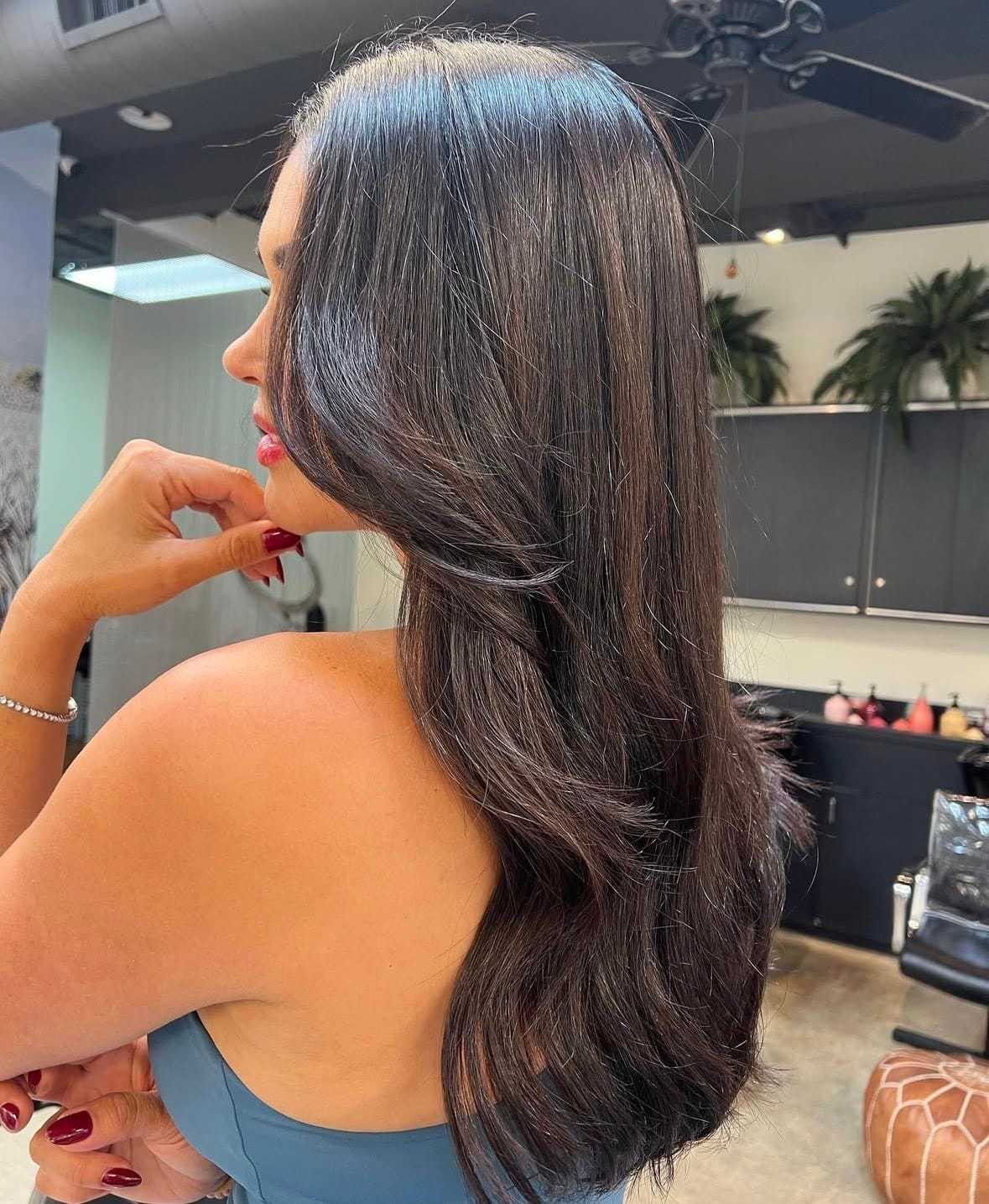 Woman in salon with long, shiny brown hair flowing elegantly over shoulder.