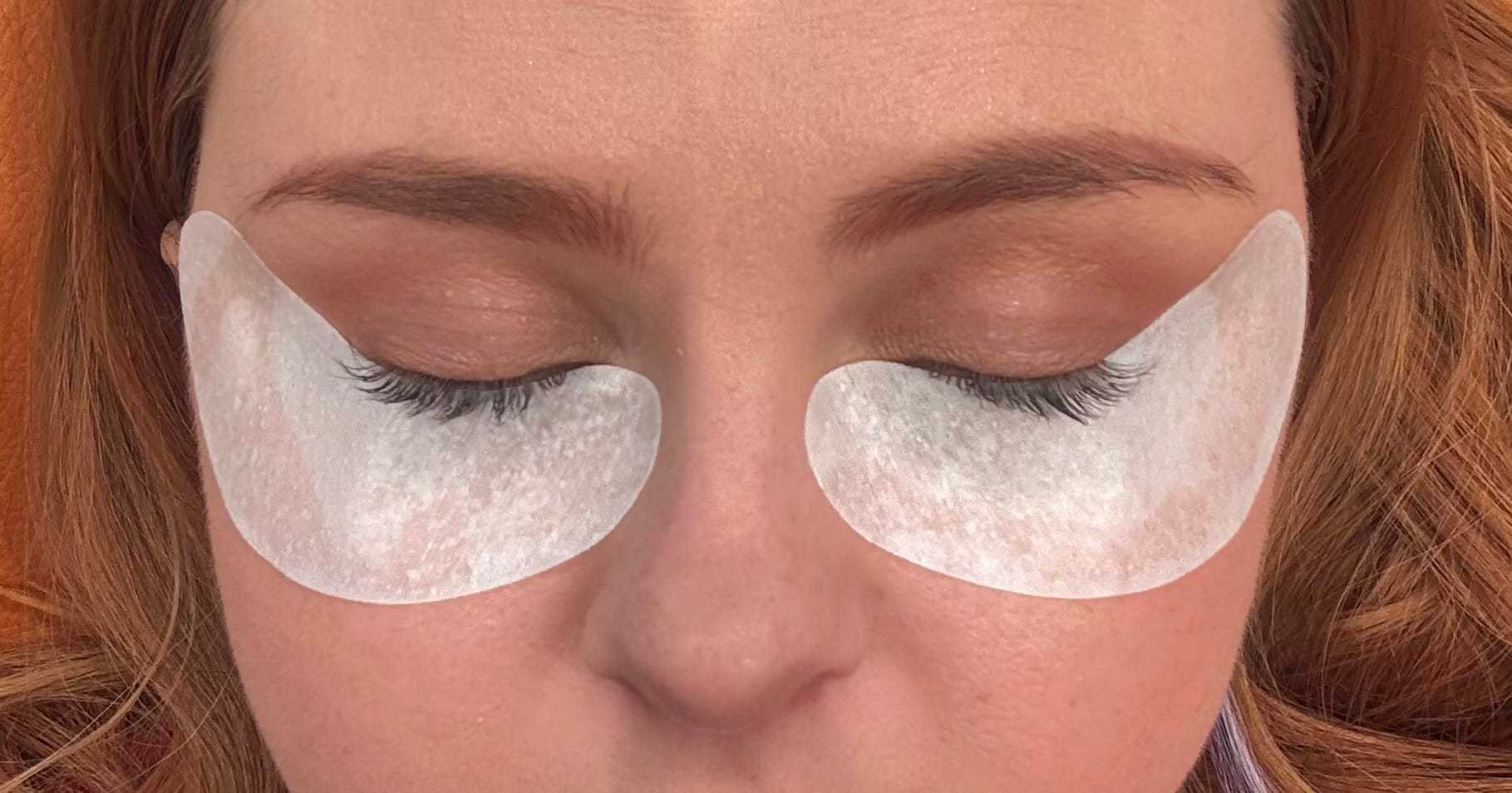 Woman with eye masks closed, relaxing during a skincare treatment.