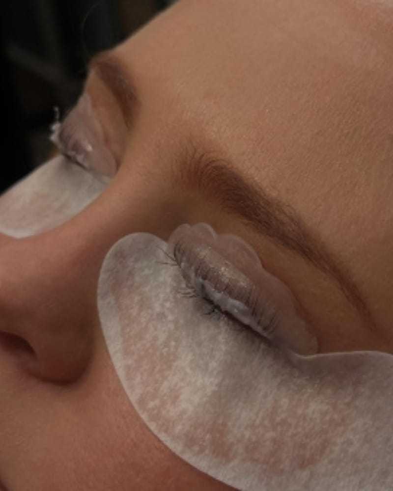 Under-eye patches on closed eyes during a beauty treatment.